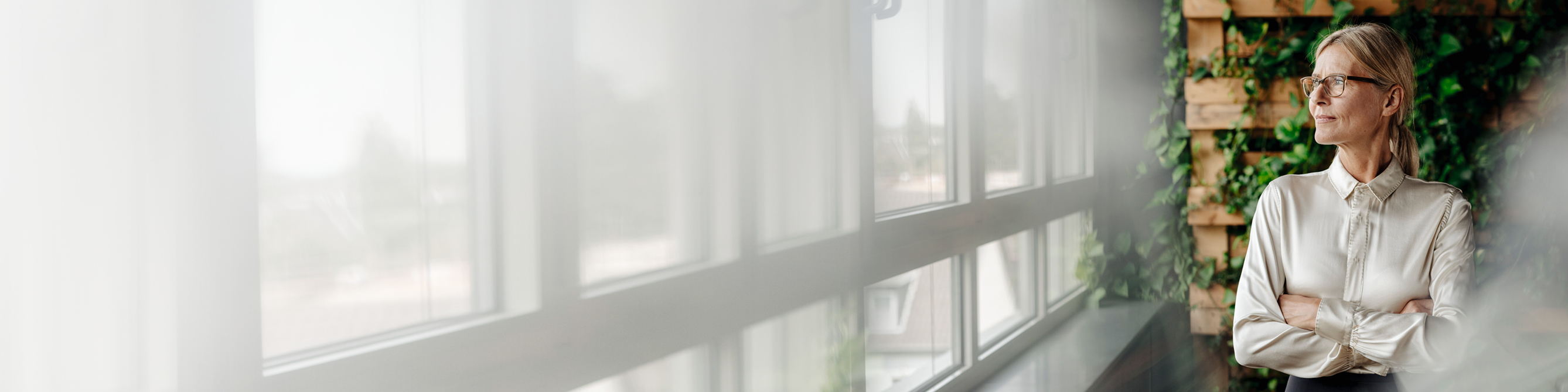 Eine Frau lässt ihren Blick aus dem Fenster ihres Büros schweifen.