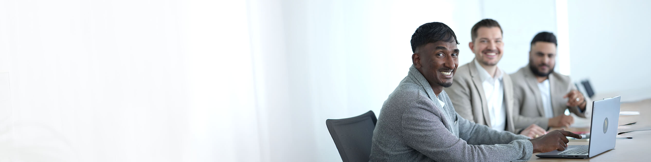 Mehrere Kollegen sitzen an einem Tisch und nutzen ihre Laptops für ein gemeinsames Projekt.