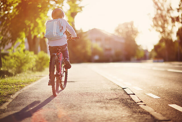 Schulkind mit Tornister fährt mit dem Fahhrrad auf dem Bürgerstersteig